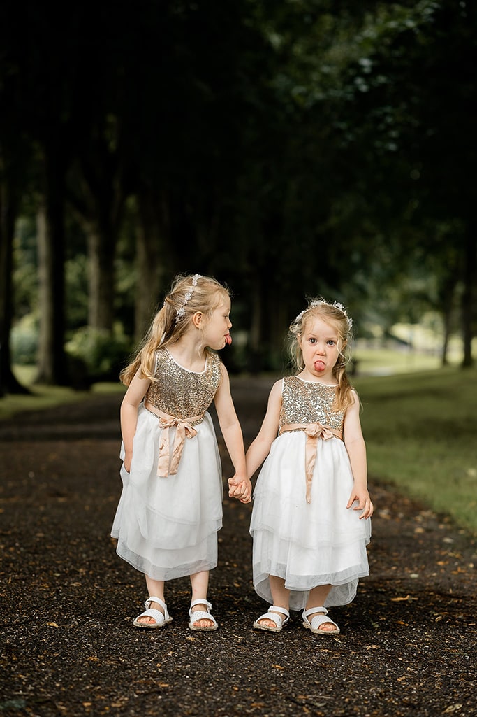 Hilarious photo of twin girl bridesmaids poking their tongues out at each other, taken by Emma Seaney, local wedding photographer